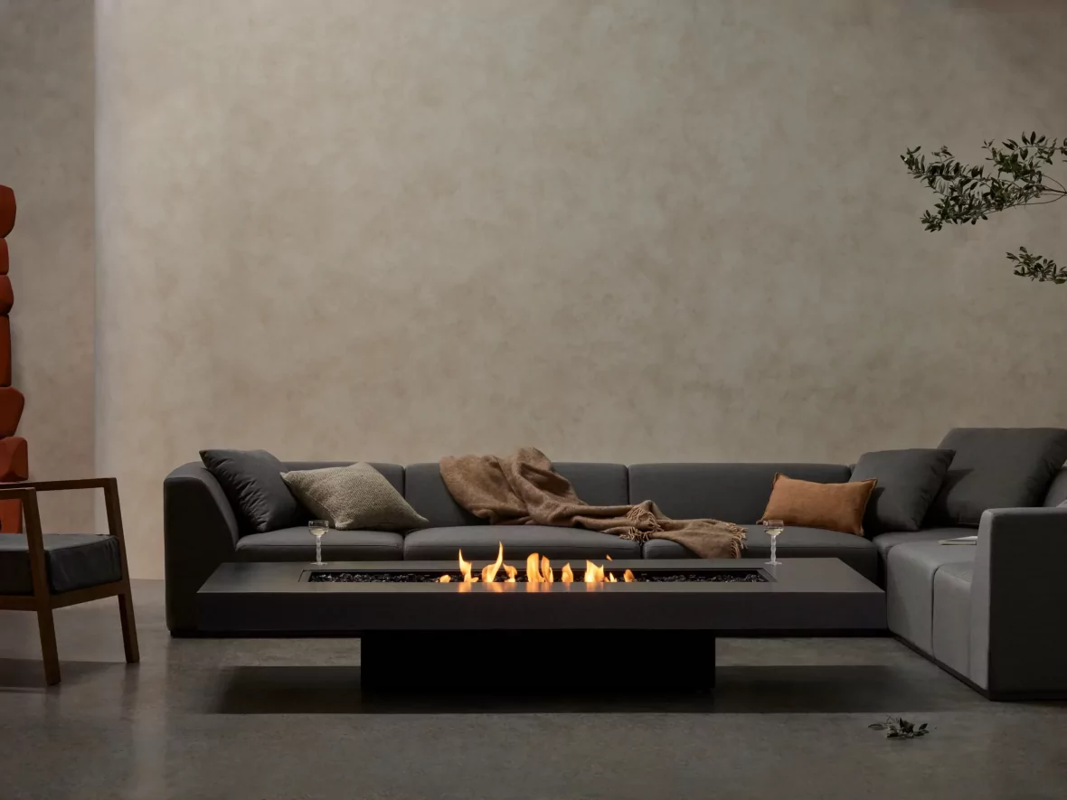 Mesa de fuego EcoSmart Fire Gin 90 delante de un sofá de exterior